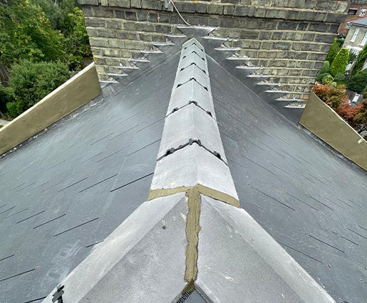 Slate roof installation with a detailed view of the ridge and adjacent roofing sections.