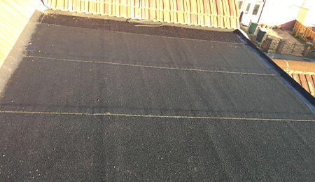 Flat roofing installation with a view of the adjoining roof structure.