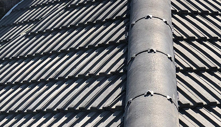 Roofing tiles with a vertical chimney flue on a sloped roof.